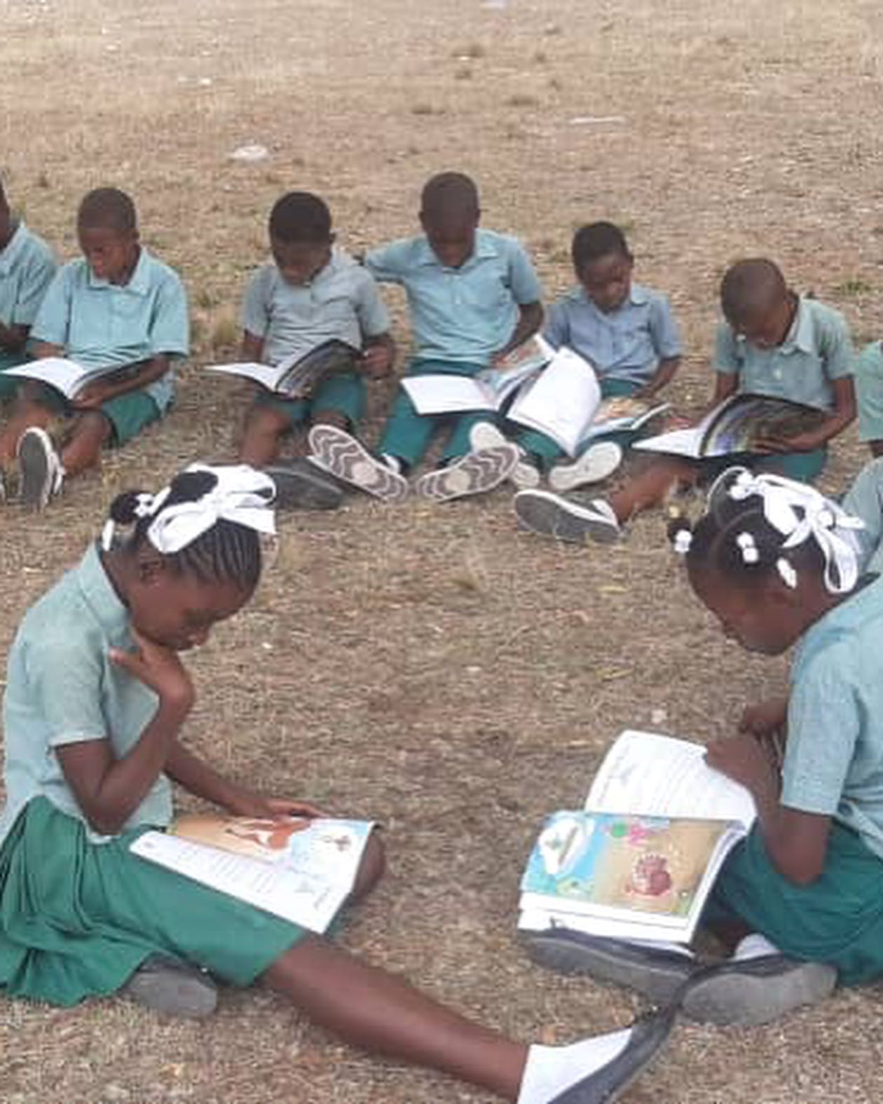 Three girls reading Nan Jaden Amoni in a Haitian classroom
