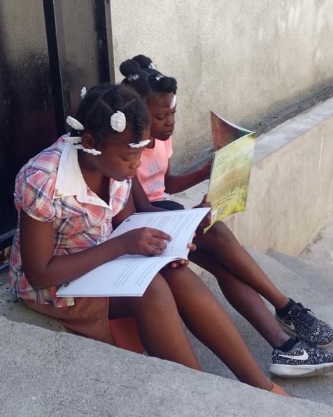 Children reading Nan Jaden Amoni outdoors in Haiti