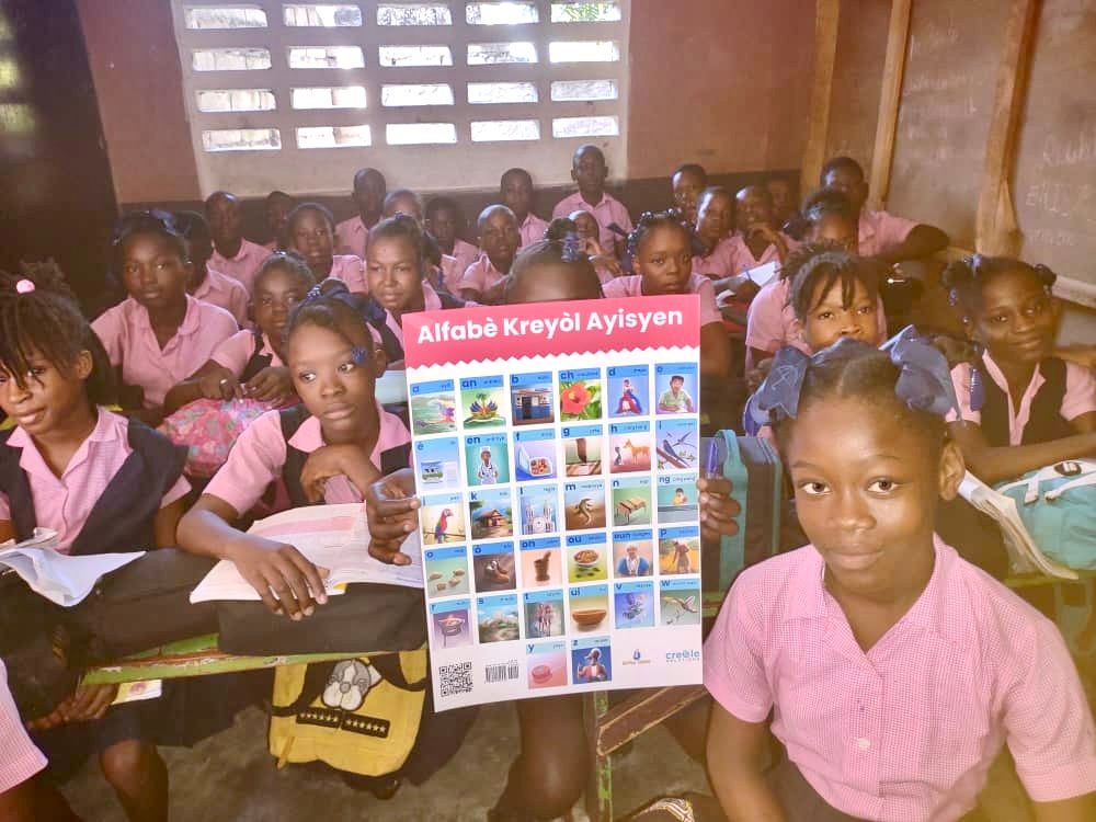 A class in Haiti showing the Alfabè Kreyòl Ayisyen poster