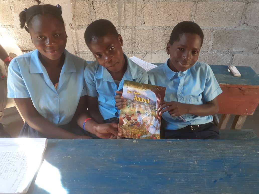 Three students in Haiti holding Nan Jaden Amoni
