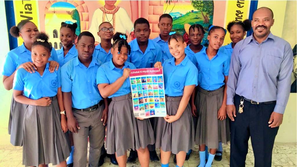A girls' class in Haiti displaying the Alfabè Kreyòl Ayisyen poster